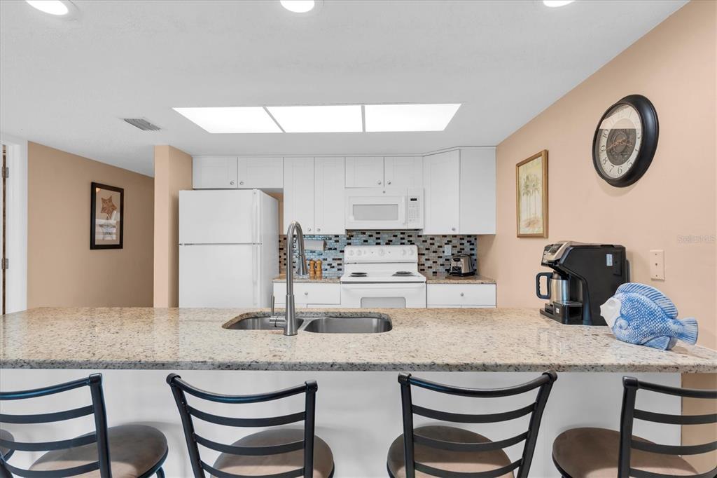 19610 Gulf Boulevard, Unit 308 Indian Rocks Beach, FL 33785 - Photo 10 of 41 a kitchen with granite countertop white cabinets and stainless steel appliances
