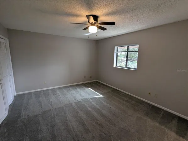 an empty room with ceiling fan and window