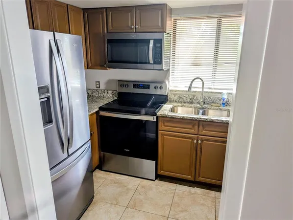 a kitchen with stainless steel appliances granite countertop a refrigerator a stove a sink and a microwave