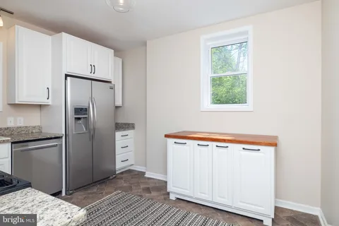 a view of a kitchen with refrigerator and wooden floor