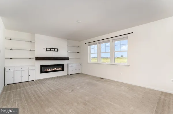 an empty room with windows and fireplace