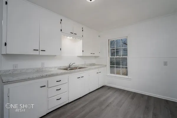 a kitchen with granite countertop white cabinets and sink
