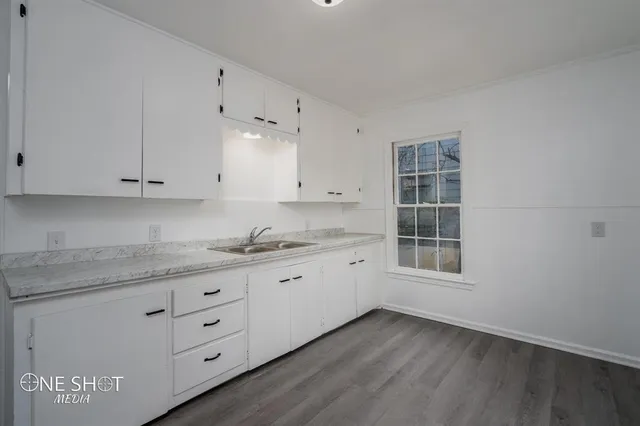a kitchen with granite countertop white cabinets and sink