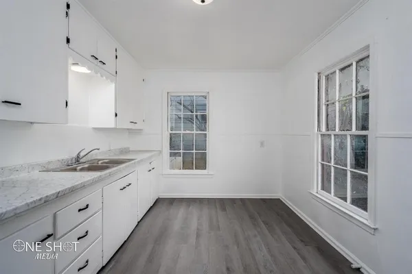 a kitchen with granite countertop white cabinets and window
