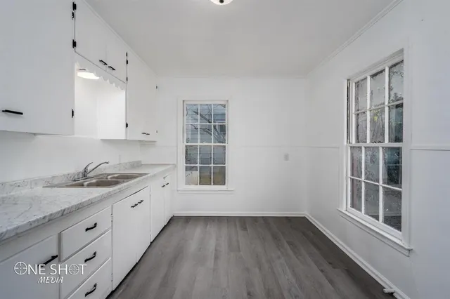 a kitchen with granite countertop white cabinets and window