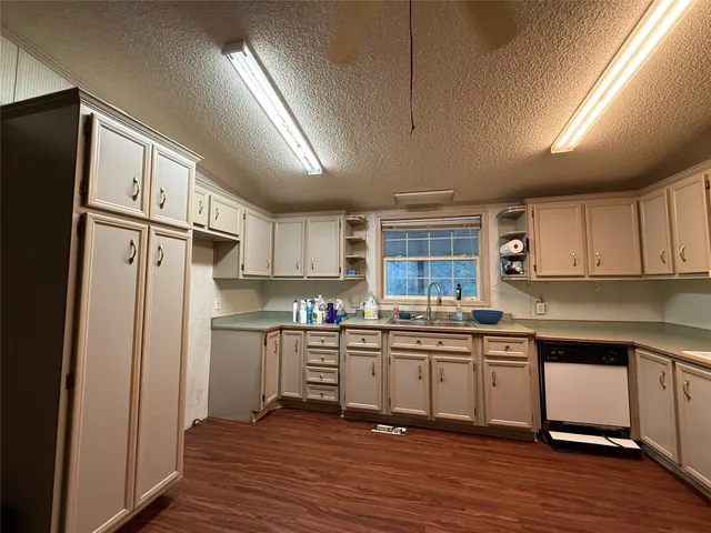 a kitchen with stainless steel appliances granite countertop a refrigerator a sink dishwasher a stove and white cabinets with wooden floor