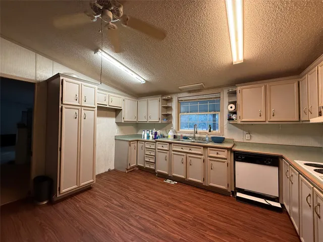 a kitchen with stainless steel appliances granite countertop a refrigerator a sink dishwasher a stove and white countertops with wooden floor