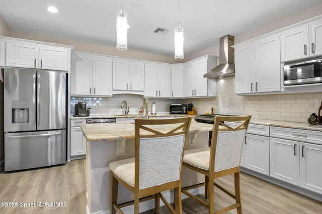 a kitchen with stainless steel appliances granite countertop a refrigerator a stove a sink dishwasher and a refrigerator with wooden floor