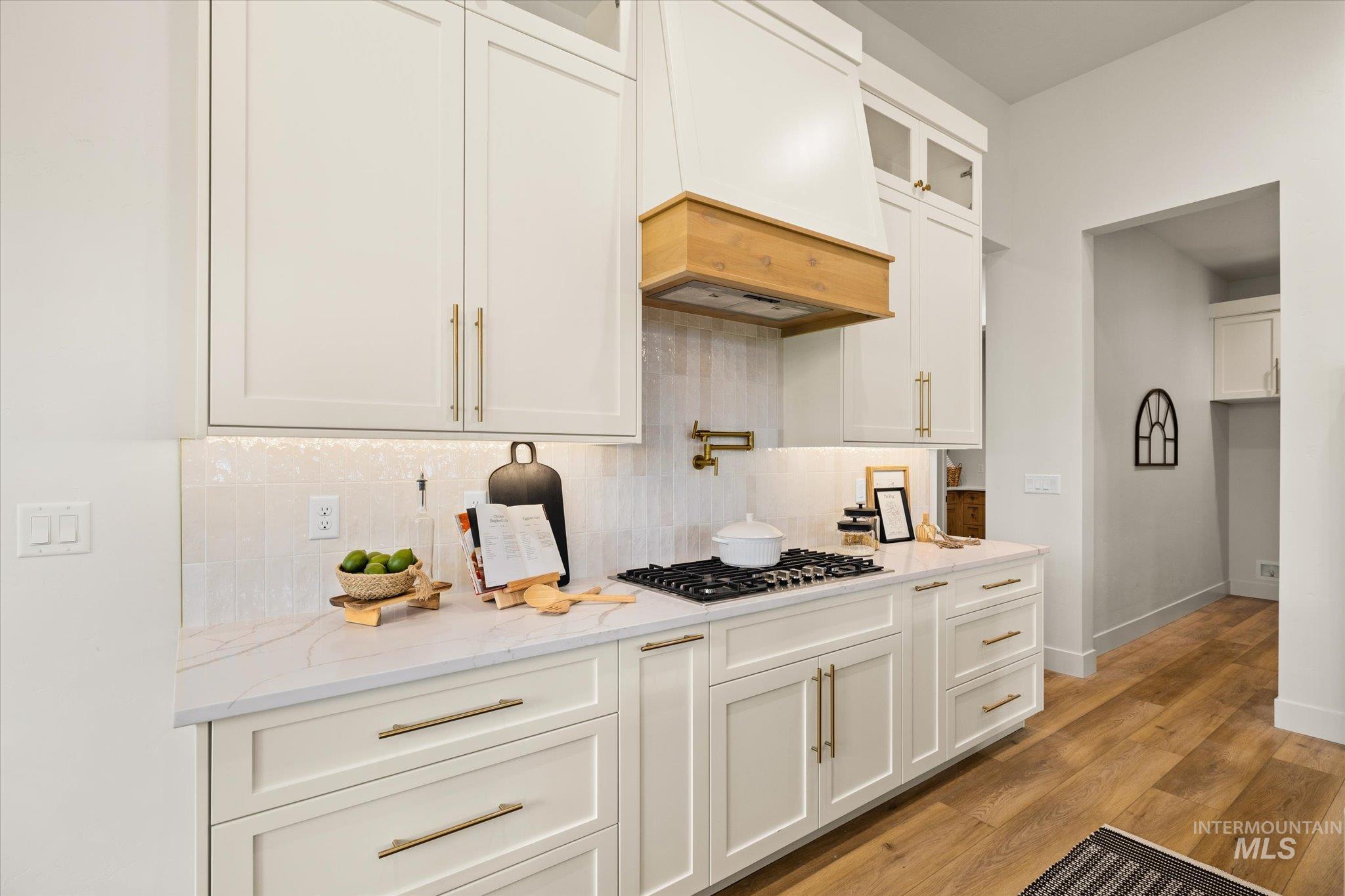 22909 Cirrus Vw Court Caldwell, ID 83607 - Photo 16 of 50 Kitchen with glass insert cabinets, backsplash, white cabinets, light stone counters, and custom range hood