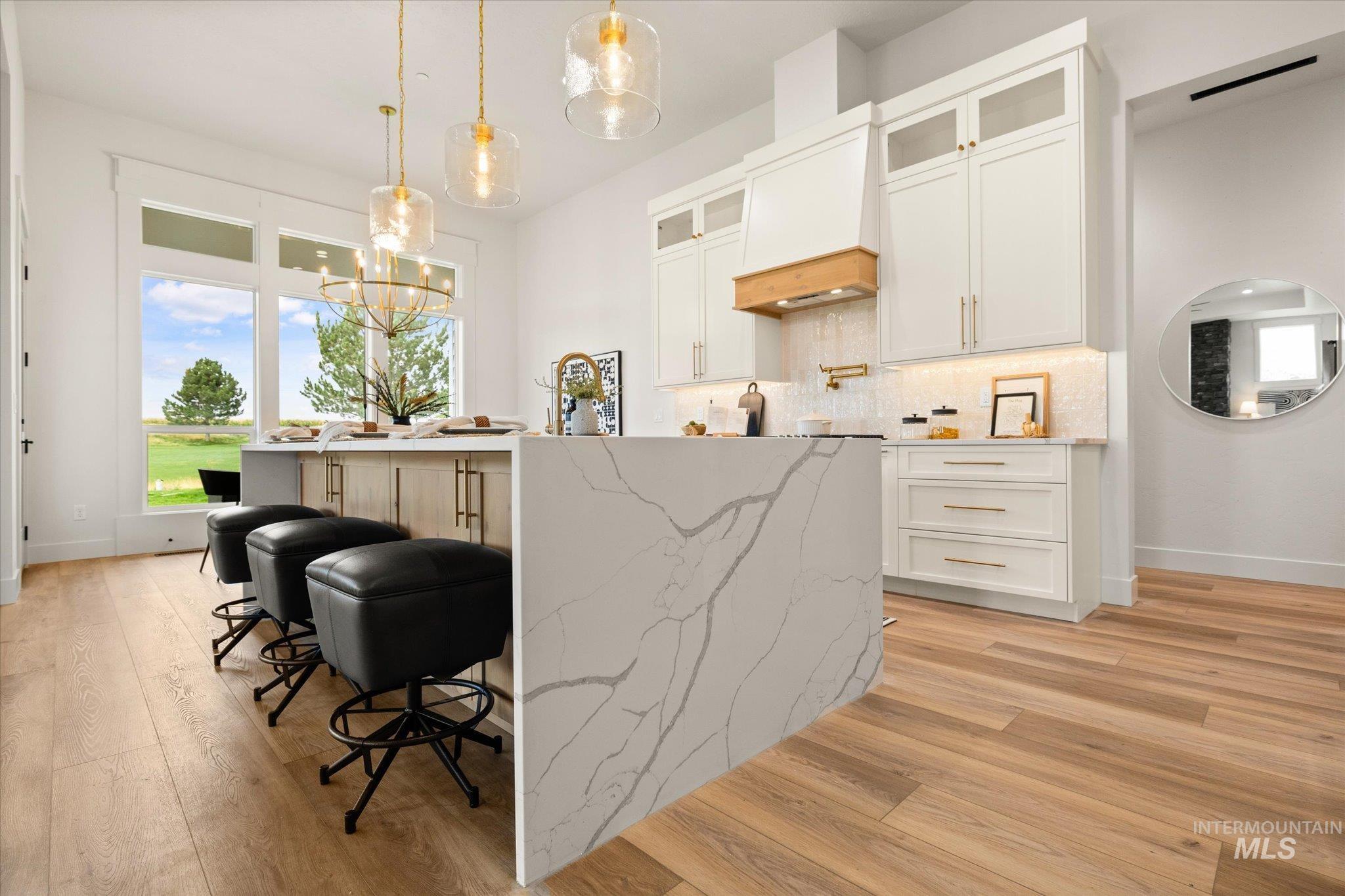 22909 Cirrus Vw Court Caldwell, ID 83607 - Photo 20 of 50 Kitchen featuring glass insert cabinets, hanging light fixtures, a breakfast bar, white cabinets, and a center island with sink
