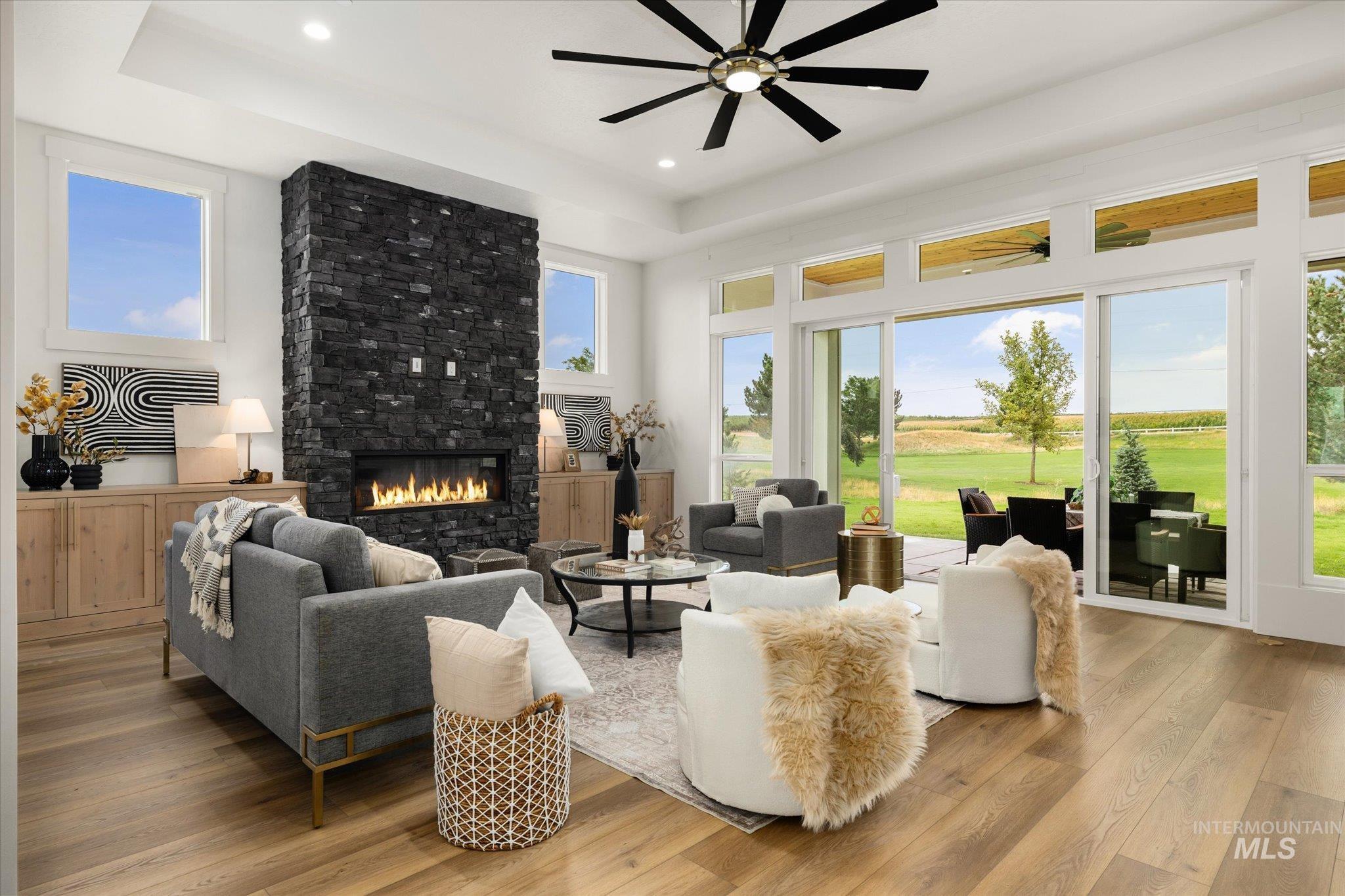 22909 Cirrus Vw Court Caldwell, ID 83607 - Photo 7 of 50 Living room with light wood-style floors, a large fireplace, healthy amount of natural light, a raised ceiling, and recessed lighting