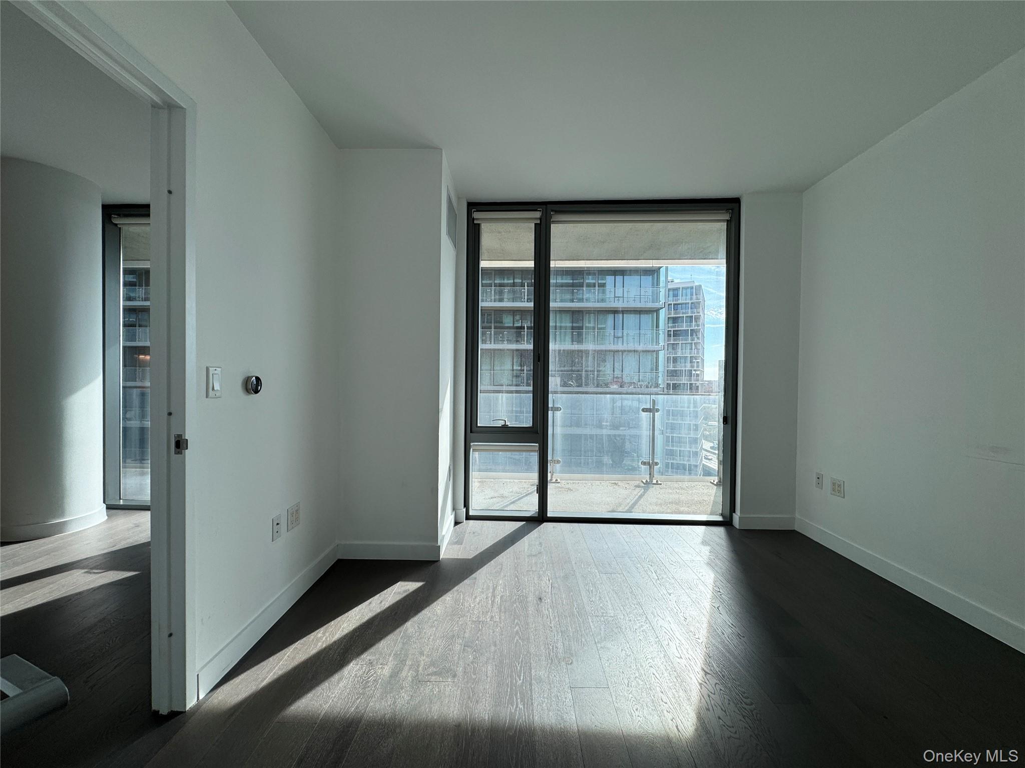 131-03 40 Road, Unit 16P Queens, NY 11354 - Photo 2 of 13 an empty room with wooden floor and cabinet