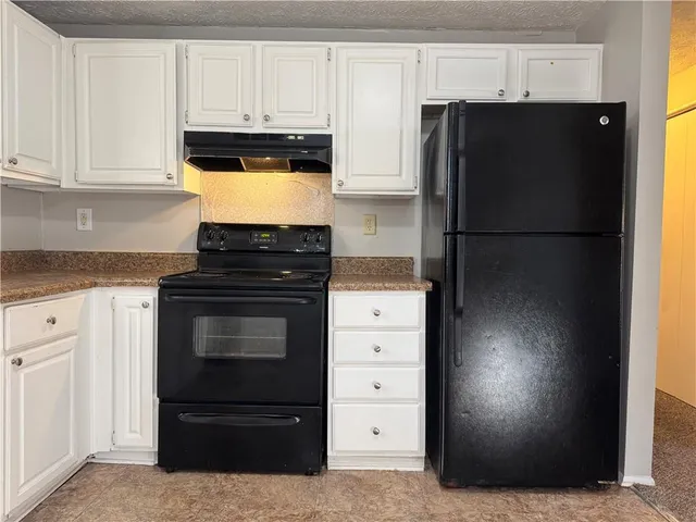 a kitchen with granite countertop white cabinets and refrigerator