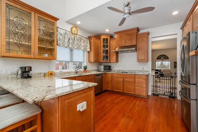 a kitchen with stainless steel appliances granite countertop a sink a stove and a wooden floors