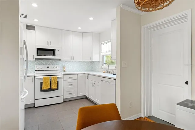 a kitchen with white cabinets and black appliances