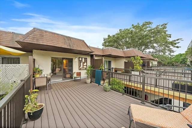 a view of a house with a wooden deck and furniture