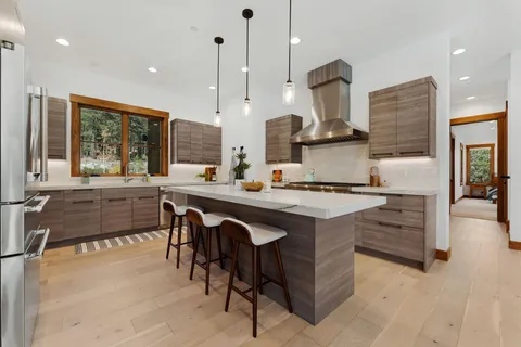 a kitchen with stainless steel appliances granite countertop a stove a sink a oven and a refrigerator with wooden floor