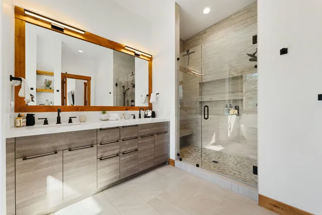 a bathroom with a double vanity sink mirror and shower