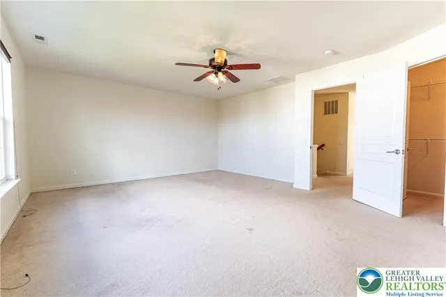 an empty room with closet and a chandelier fan