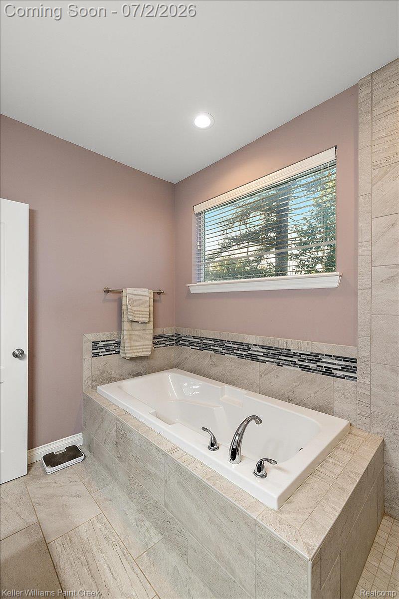 54230 Card Road Macomb, MI 48042 - Photo 54 of 73 Built-in soaking tub with chrome fixtures, surrounded by light-toned tile and a decorative mosaic accent band