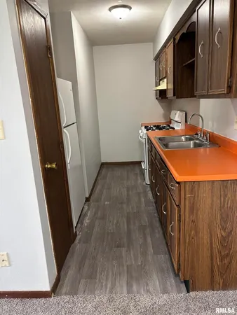 a kitchen with wooden cabinets a sink a stove and a refrigerator