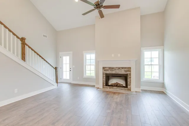 a view of an empty room with wooden floor fireplace and a window