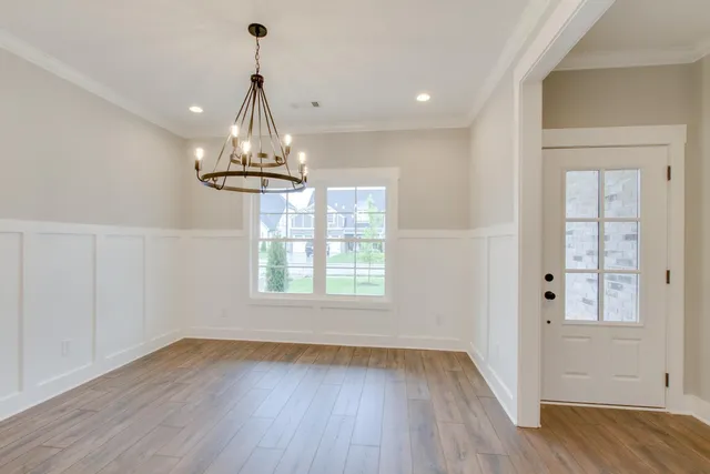 a view of a room with wooden floor chandelier and window