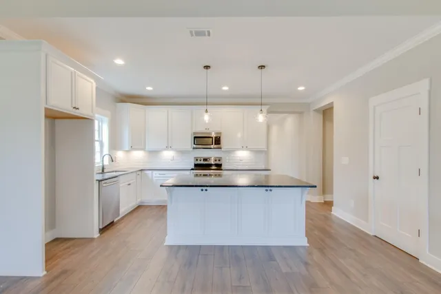 a large kitchen with stainless steel appliances granite countertop a stove a sink and a refrigerator