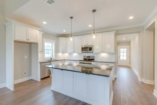 a kitchen with kitchen island granite countertop a sink cabinets and wooden floor