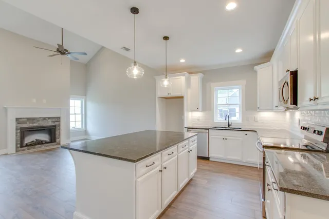a kitchen with granite countertop a sink a counter space appliances and cabinets