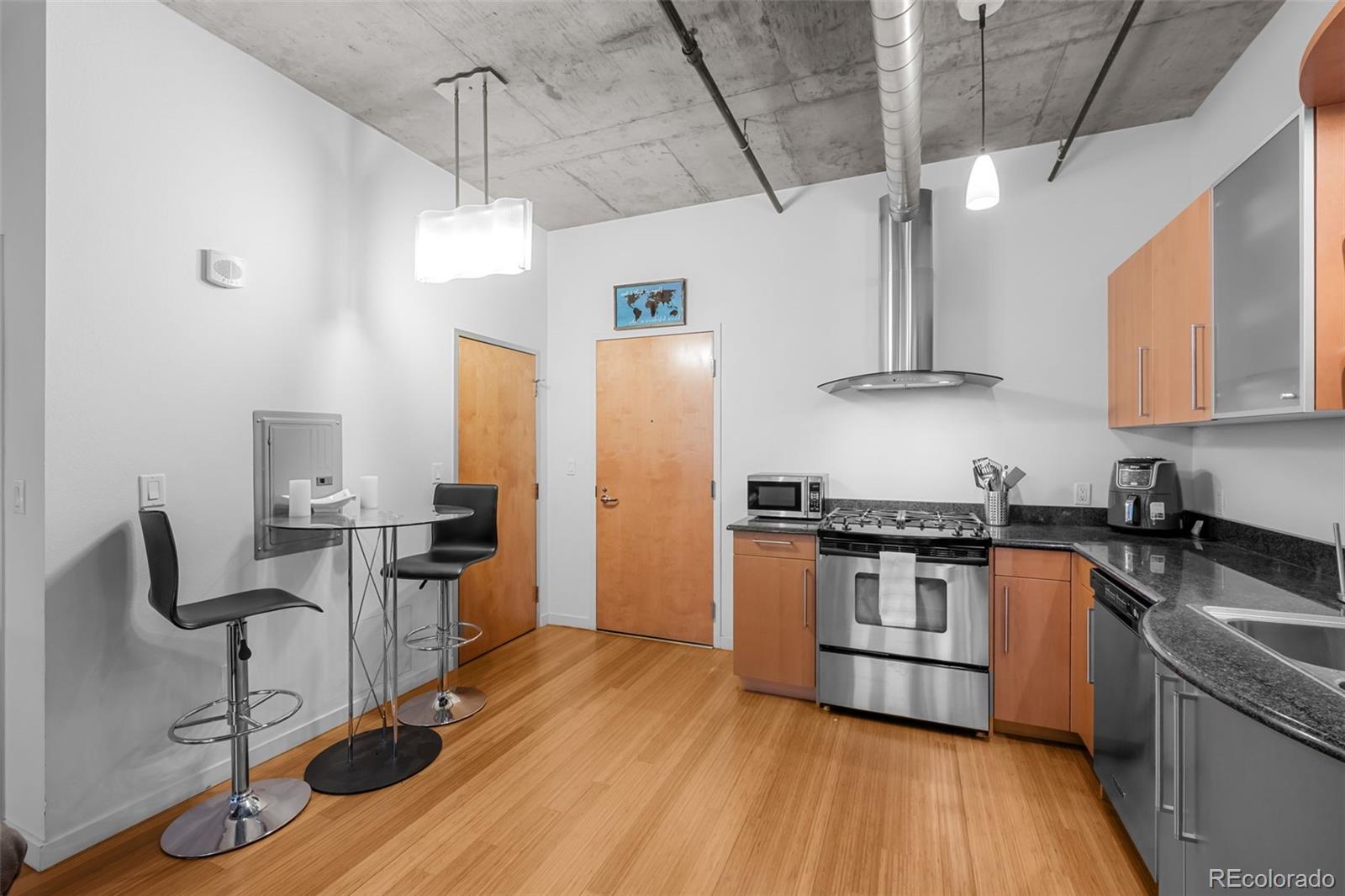 1401 Wewatta Street, Unit 311 Denver, CO 80202 - Photo 11 of 34 a kitchen with stainless steel appliances granite countertop a stove a refrigerator a sink dishwasher a dining table and chairs with wooden floor