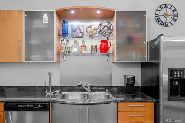 a kitchen with stainless steel appliances granite countertop a stove a refrigerator a sink dishwasher a dining table and chairs with wooden floor