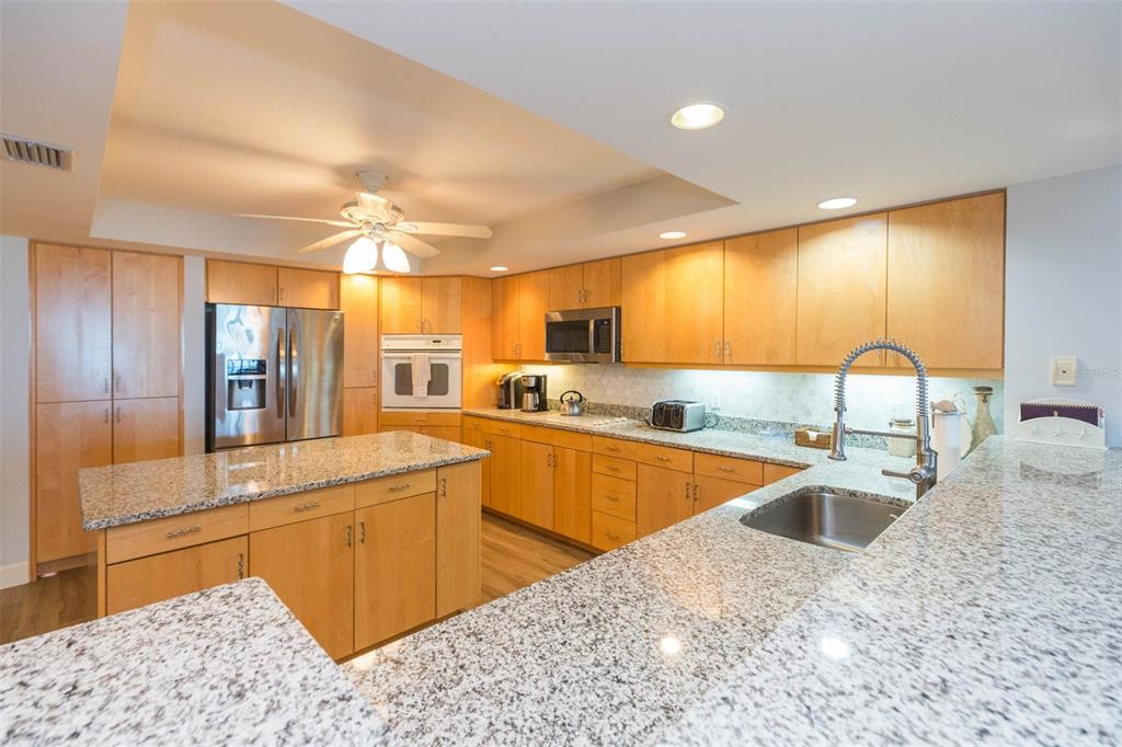 16326 Gulf Boulevard, Unit 109 Redington Beach, FL 33708 - Photo 11 of 63 a large kitchen with stainless steel appliances kitchen island granite countertop a sink and cabinets