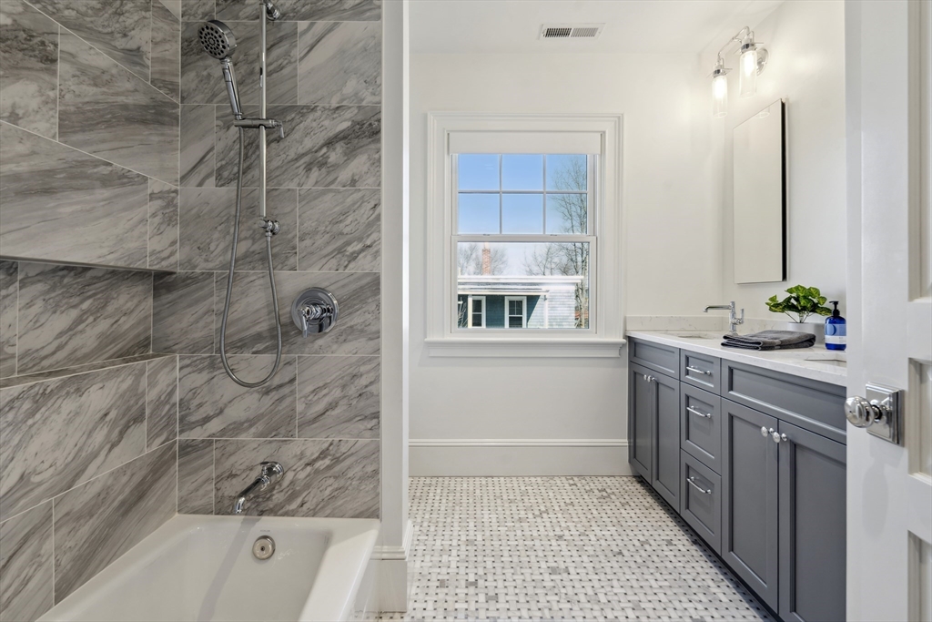 73 Upland Road Cambridge, MA 02140 - Photo 28 of 42 a bathroom with a granite countertop sink a large mirror and shower