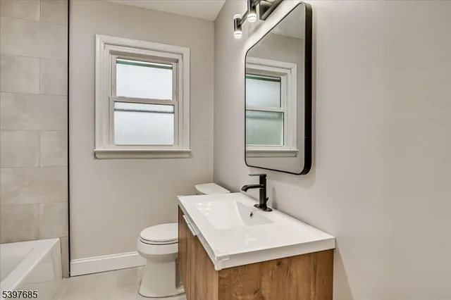 a bathroom with a toilet a sink a mirror and a window