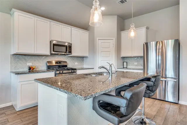 a kitchen with kitchen island granite countertop a sink appliances and cabinets
