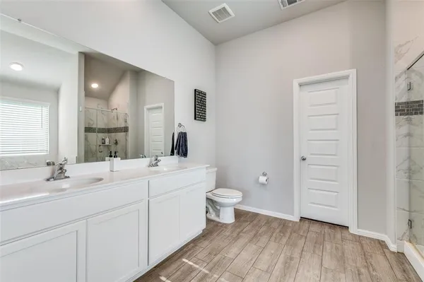 a bathroom with a double vanity sink a toilet and a mirror