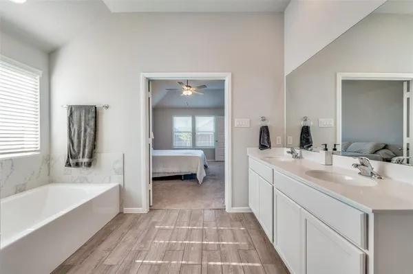 a spacious bathroom with a tub sink and mirror