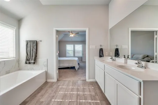 a spacious bathroom with a tub sink and mirror