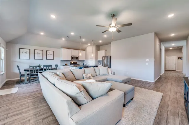 a living room with furniture and a dining table with wooden floor