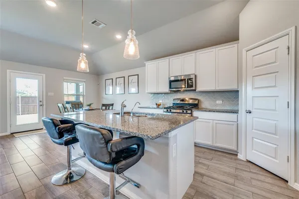 a kitchen with granite countertop white cabinets and stainless steel appliances