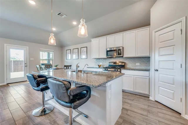 a kitchen with granite countertop white cabinets and stainless steel appliances
