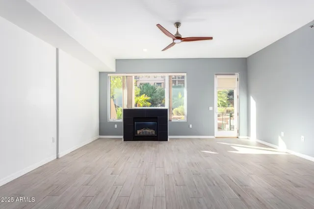 a view of an empty room with a window and wooden floor