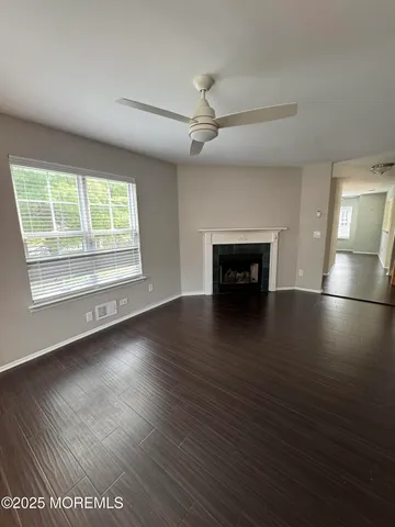 an empty room with wooden floor fireplace and windows