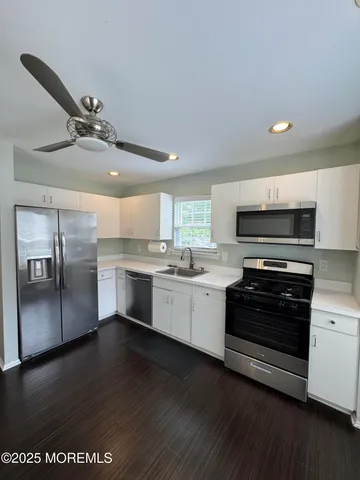 a kitchen with stainless steel appliances a stove a sink and white cabinets