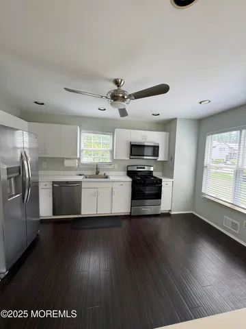 a kitchen with granite countertop a stove a sink dishwasher a refrigerator and a stove with wooden floor