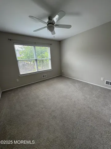 an empty room with a ceiling fan and window