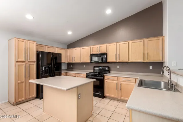 a kitchen with granite countertop a refrigerator stove top oven and sink