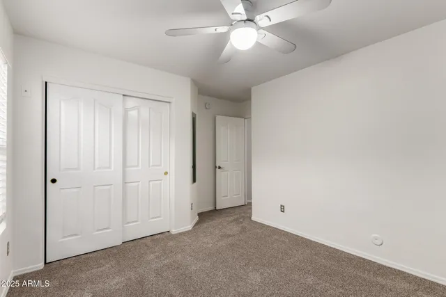 an empty room with a ceiling fan and a window