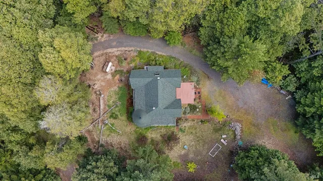 an aerial view of a house with outdoor space and trees all around